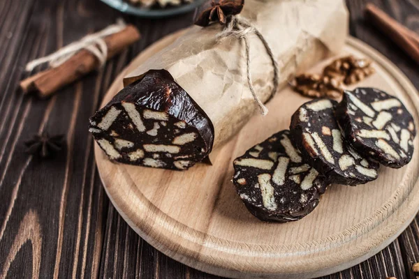 Ahşap arka plan üzerinde çikolata sosis. Tatlı yaptı bisküvi, çikolata ve fındık bir ahşap tahta üzerine dilimlenmiş