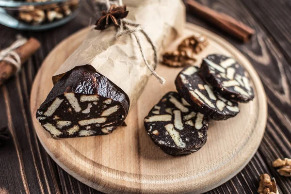 Chocolate sausage on a wooden background. Dessert made of biscuits, chocolate and nuts is sliced on a wooden board