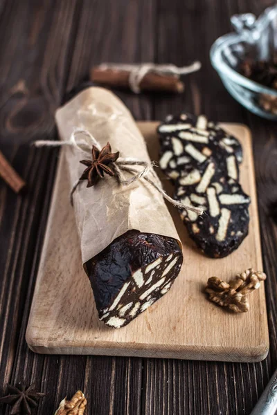 Chocolate sausage on a wooden background. Dessert made of biscuits, chocolate and nuts is sliced on a wooden board