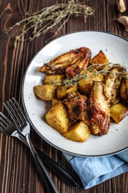 Ev yapımı Fırında tavuk kanatlı patates ve rustik bir arka plan üzerine sarımsak