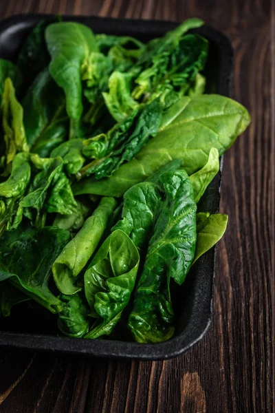 Leaves of green spinach. Fresh organic spinach on a wooden table. Vegan food, healthy food. Dark rustic style photo.