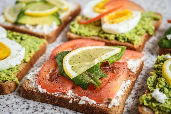 Homemade healthy avocado and egg toasts. Toast, avocado, egg, tomatoes, spinach, cheese Feta, lemon. Organic healthy food. Clean healthy eating