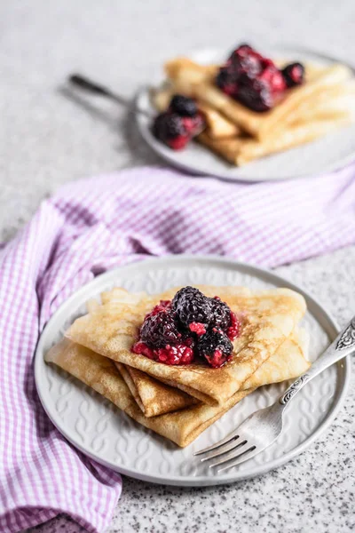 Pancakes with berries and honey on a gray background. Pancake week. Delicious breakfast of pancakes with jam.