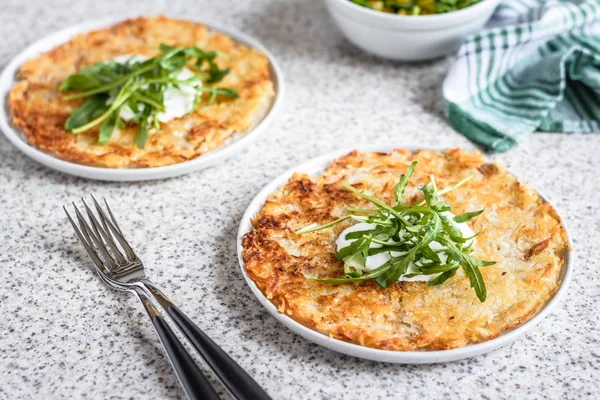 Mısır ve roket salatası ile İsviçre patates Rosti gri bir arka planda hizmet vermiştir. Geleneksel İsviçre yemeği