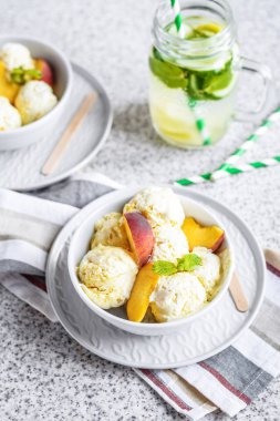 Gri bir arka planda bir plaka nane ve taze şeftali dilimleri ile lezzetli ev yapımı şeftali dondurması