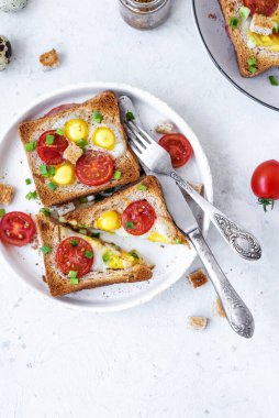 Jambon ve sahanda yumurtalı sandviç, jambon ve domatesli sahanda yumurta ve gri beton masa. Yakın çekim, üst görünüm.
