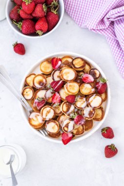 Hafif arka planda çilekli ev yapımı mini krepler. Lezzetli bir kahvaltı. Gıda trend. Bebek maması.