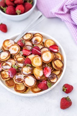 Hafif arka planda çilekli ev yapımı mini krepler. Lezzetli bir kahvaltı. Gıda trend. Bebek maması.