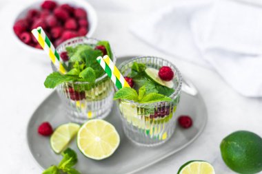 Limonlu mojito kokteyli, ahududu ve naneli bir bardak. Taze yaz kokteyli. Gri arka planda yaz mojito 'su