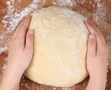 Üstten görünüm çocuk el ahşap masa üzerinde bir hamur yapmak