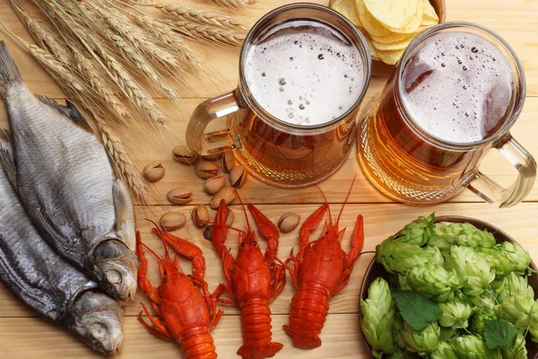 Glass beer with crawfish, hop cones and wheat ears on light wooden background. Beer brewery concept. Beer background. top view