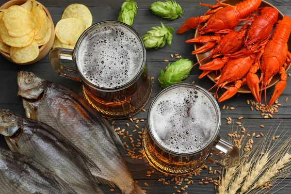 Glass beer with crawfish, dried fish and hop cones on dark wooden background. Beer brewery concept. Beer background. top view