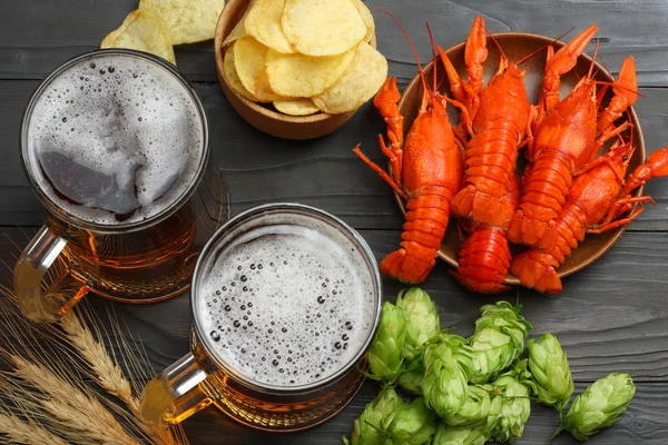 Glass beer with crawfish, hop cones and wheat ears on dark wooden background. Beer brewery concept. Beer background. top view