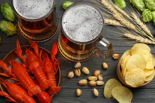 Glass beer with crawfish, hop cones and wheat ears on dark wooden background. Beer brewery concept. Beer background. top view