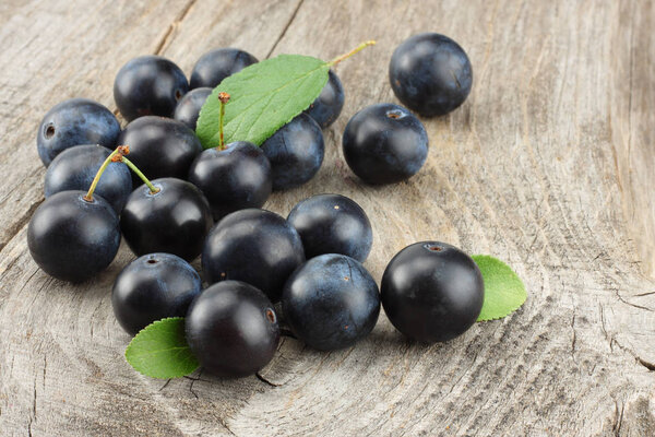 blackthorn berries with green leaf on old wooden table