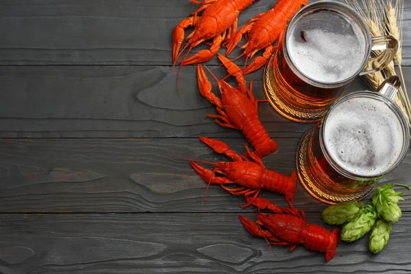 Glass beer with crawfish, hop cones and wheat ears on dark wooden background. Beer brewery concept. Beer background. top view with copy space