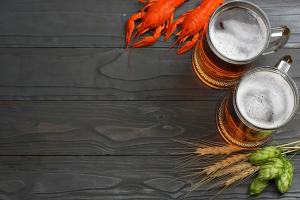 Glass beer with crawfish, hop cones and wheat ears on dark wooden background. Beer brewery concept. Beer background. top view with copy space