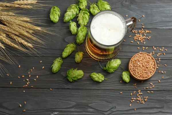 Glass beer with hop cones and wheat ears on dark wooden background. Beer brewery concept. Beer background. top view with copy space