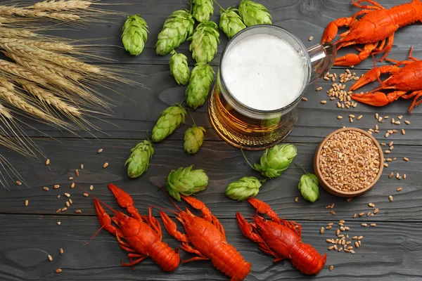 Glass beer with crawfish, hop cones and wheat ears on dark wooden background. Beer brewery concept. Beer background. top view with copy space