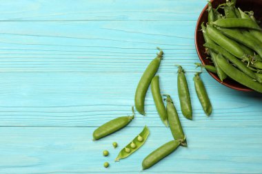 Mavi ahşap zemin üzerine kase taze bezelye. Kopya alanı ile üstten görünüm.