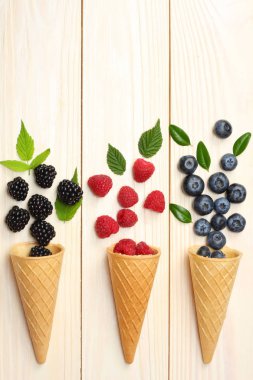 yaban mersini, böğürtlen, ahududu ahşap masa lambası arka plan üzerinde dondurma koni karışımı. kopya alanı ile üstten görünüm