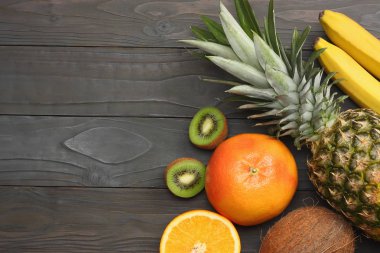 taze Hindistan cevizi, muz, kivi, portakal ve koyu ahşap arka plan üzerinde ananas karışımı. kopya alanı ile üstten görünüm