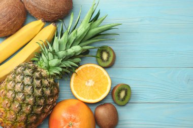 taze Hindistan cevizi, muz, kivi, portakal ve mavi ahşap arka plan üzerinde ananas karışımı. kopya alanı ile üstten görünüm