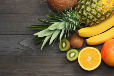taze Hindistan cevizi, muz, kivi, portakal ve koyu ahşap arka plan üzerinde ananas karışımı. kopya alanı ile üstten görünüm