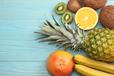 taze Hindistan cevizi, muz, kivi, portakal ve mavi ahşap arka plan üzerinde ananas karışımı. kopya alanı ile üstten görünüm