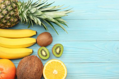 taze Hindistan cevizi, muz, kivi, portakal ve mavi ahşap arka plan üzerinde ananas karışımı. kopya alanı ile üstten görünüm