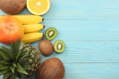 taze Hindistan cevizi, muz, kivi, portakal ve mavi ahşap arka plan üzerinde ananas karışımı. kopya alanı ile üstten görünüm 