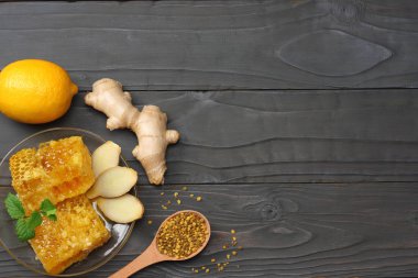 sağlıklı arka plan. Tatlım, petek, limon, koyu ahşap masa üzerinde zencefil. Kopya alanı ile üstten görünüm