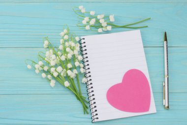 zambak vadideki mavi ahşap arka plan üzerinde beyaz kağıt ile. kopya alanı ile üstten görünüm