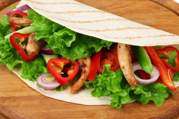 Tortilla envelopper avec de la viande de poulet frit et légumes sur planche de bois isolé sur fond blanc — Photo