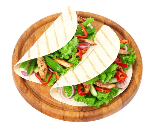 Обертка тортильи с жареным куриным мясом и овощами на деревянной доске на белом фоне — стоковое фото