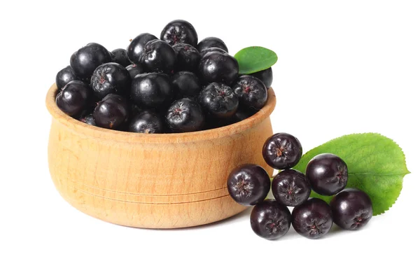 Chokeberry in wooden bowl with green leaves isolated on white background. Black aronia — Stock Photo, Image