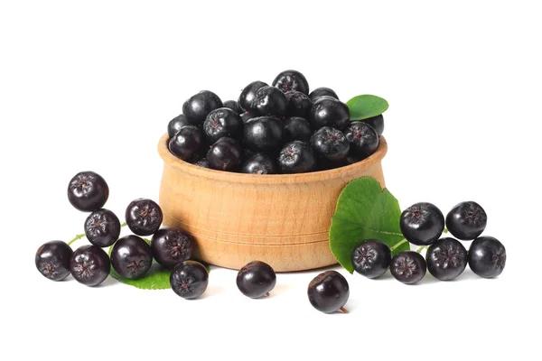 Chokeberry in wooden bowl with green leaves isolated on white background. Black aronia — Stock Photo, Image