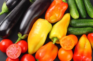 Siyah arka plan üzerinde taze çiğ sebze çeşitleri. Domates, patlıcan, soğan, biber, maydanoz, baharat. Üstte görüntü 