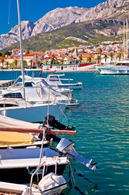 Hırvatistan 'ın Dalmaçya bölgesinde Biokovo dağı manzarası altında renkli Makarska tekneleri ve liman manzarası