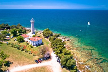Savudrija deniz feneri ve turkuaz kristal berraklığında kayalık plaj aer