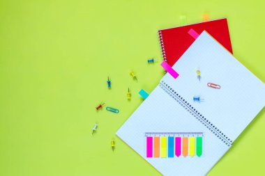 Güzel Ofis Kırtasiye düz çizgili kırmızı ve sarı notebook, kırtasiye ve ofis malzemeleri ve ataş yeşil arka plana sahip parlak masaya yatırın.