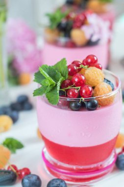 Multivitamin summer berry delicious panacotta. Sweet food with raspberries, blueberries, currants, croutons and mint, pink hydrangea bouquet, light background. Close up. clipart