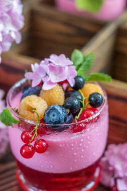 Multivitamin yaz berry lezzetli Panacott. Tatlı gıda ahududu, yaban mersini, kuş üzümü, kruton ve nane, pembe ortanca buket, koyu ahşap arka plan ile. Yakın çekim.