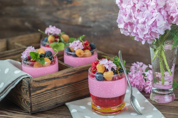 Multivitamin yaz berry lezzetli Panacott. Ahududu, yaban mersini, kuş üzümü, kruton ve nane, pembe ortanca buket, koyu ahşap arka plan ile tatlı gıda.