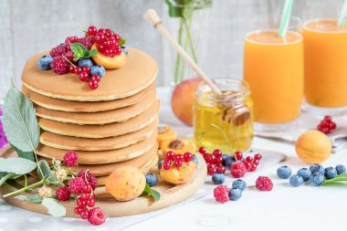 Taze lezzetli gözleme yaz ahududu, yaban mersini, kırmızı kuş üzümü, kayısı, şeftali ve nane. Pembe phlox buket, iki bardak portakal suyu, bal, açık renkli. Tatlı besleyici gıda.