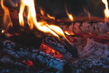 Yangında yanmış odun. Ahşap karanlık, yakın parlak alevler içinde yanıyor. Kara ateş arka plan tonda.