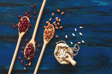 Tahta kaşık koyu mavi ahşap arka plan, mung fasulye, kırmızı börülce, beyaz fasulye, kahverengi fasulye, barbunya fasulyesi ürün yelpazesine.