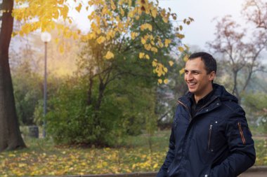 Yakışıklı adam sonbahar Park'ta yürüyordunuz şehrin güzel güneşli bir günde.