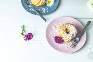 Beyaz masa, sonbahar kasımpatı pembe ve gri tabakta üzerine Hindistan cevizi cips ile lezzetli kek. Ailece kahvaltı. Metin, kopya alanı için boş alan.
