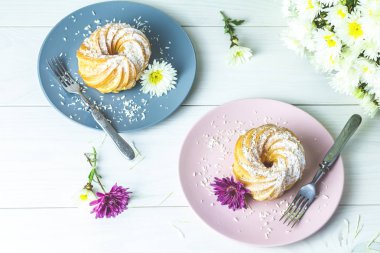 Beyaz masa, sonbahar kasımpatı pembe ve gri tabakta üzerine Hindistan cevizi cips ile lezzetli kek. Ailece kahvaltı. Metin, kopya alanı için boş alan.